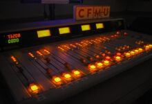 A radio station control board showing the dials glowing in a dark room