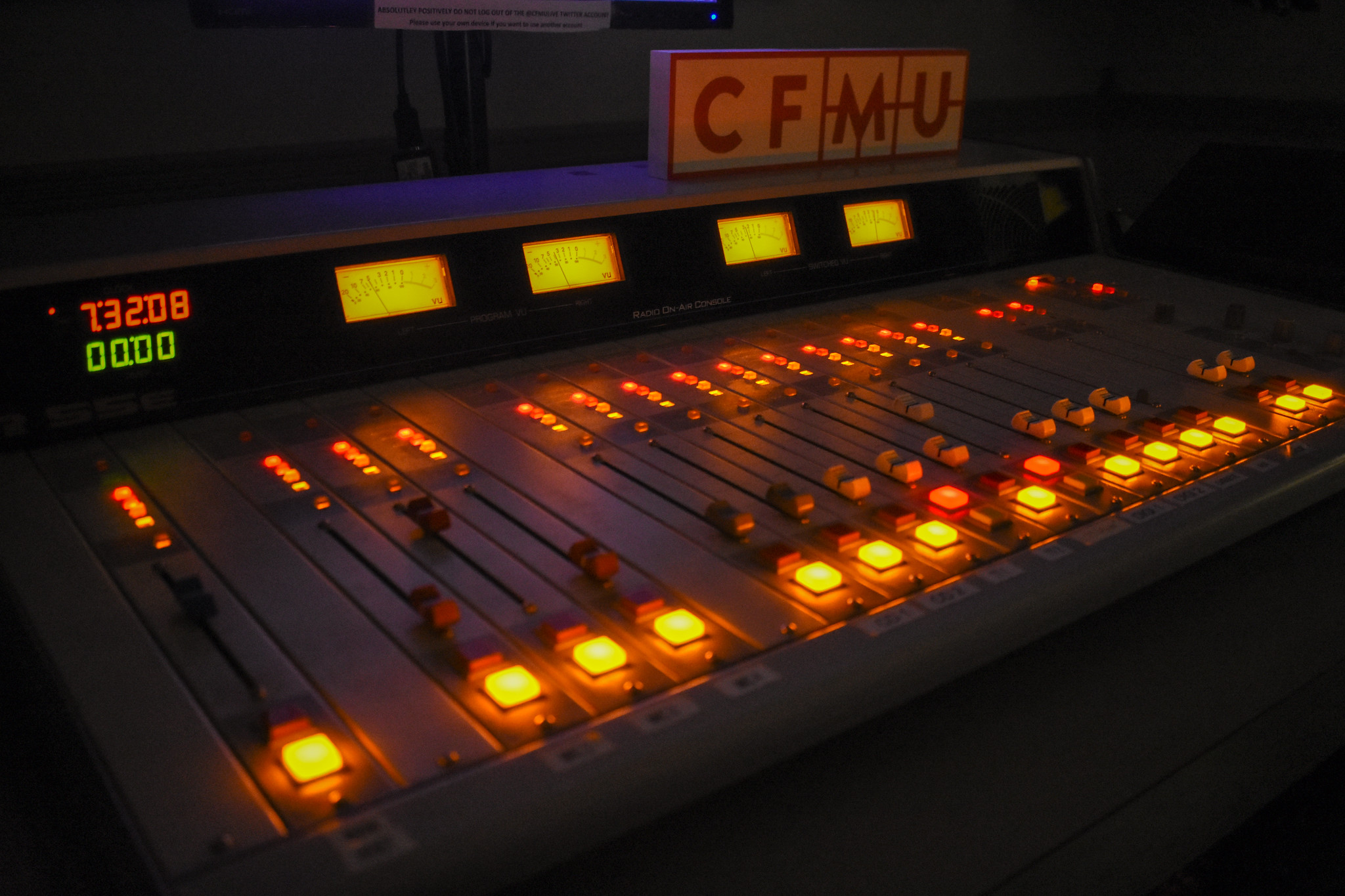 A radio station control board showing the dials glowing in a dark room