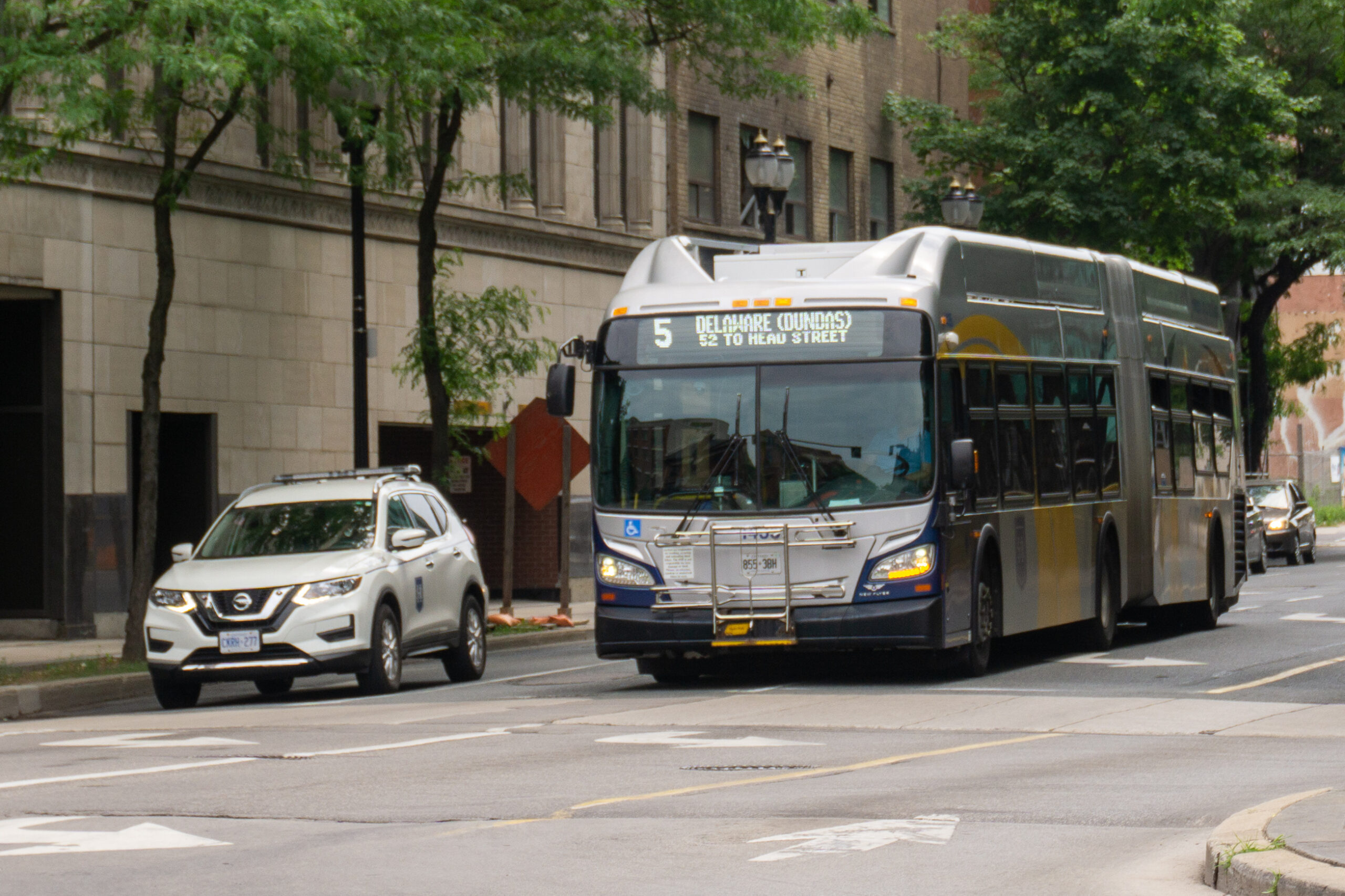 Photo shows a HSR supervisor car on the right, with a HSR 60-foot articulated bus to its left. Both are waiting at an intersection during a red light.